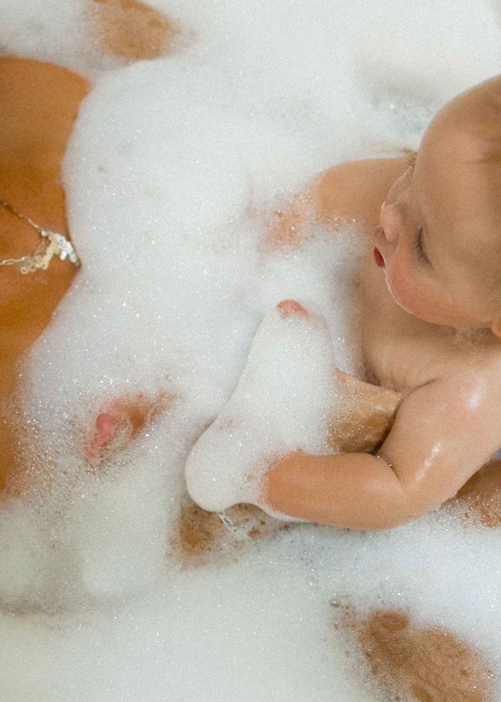 Bubbles and bath time fun fill the frame in this intimate family moment.