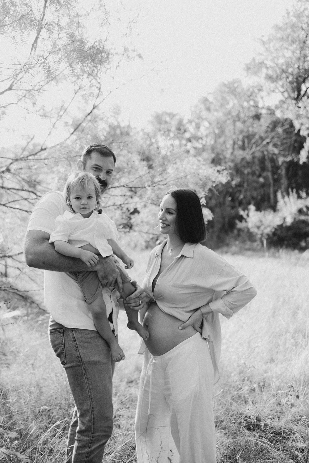 Black and white family portrait in field showing joyful interaction.