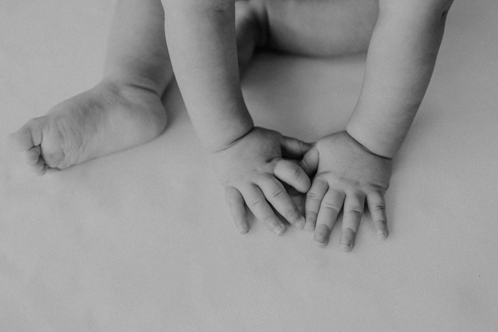 Close up black and white details of tiny baby feet and hands.