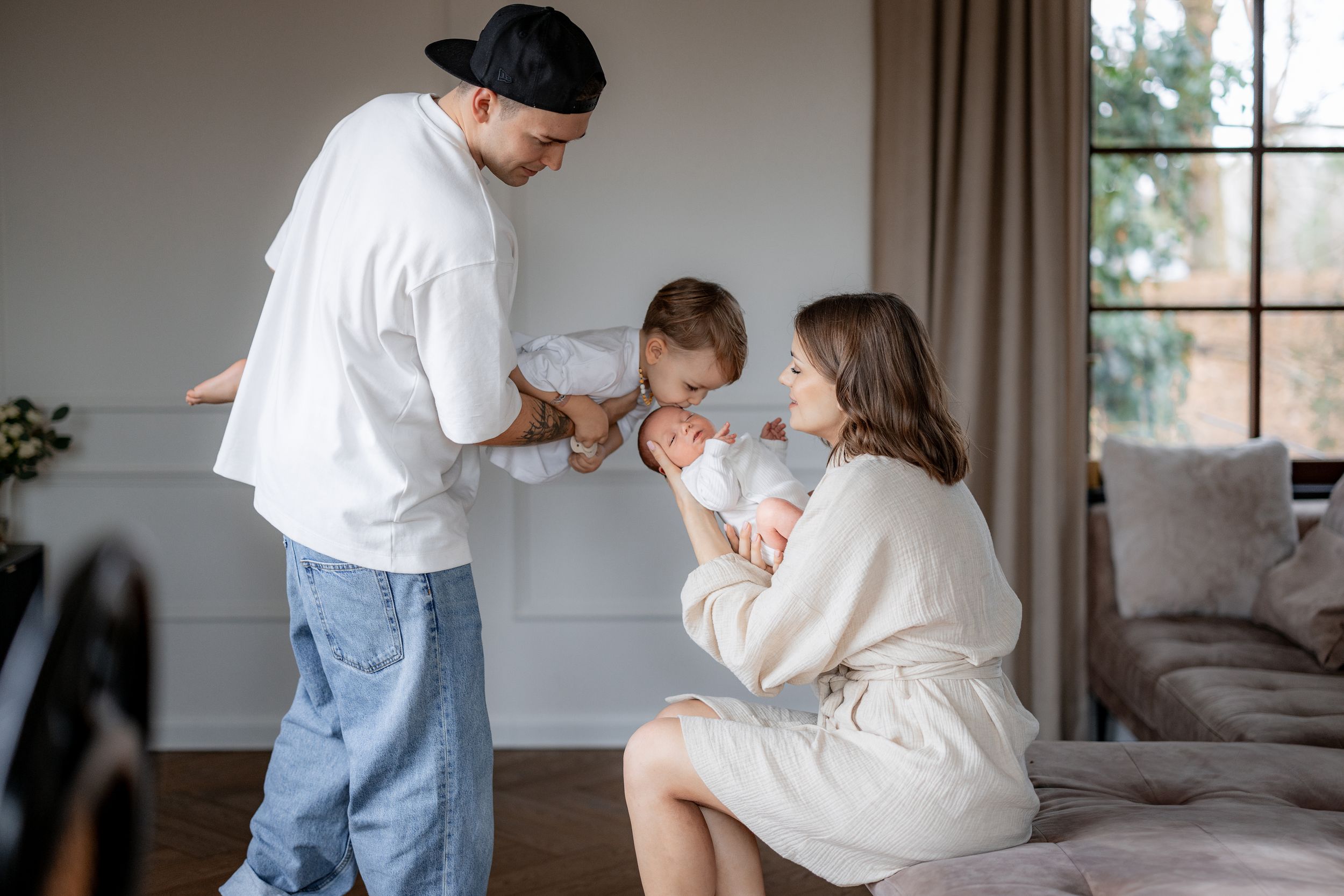 Family sharing intimate moment with newborn baby in cozy home setting.