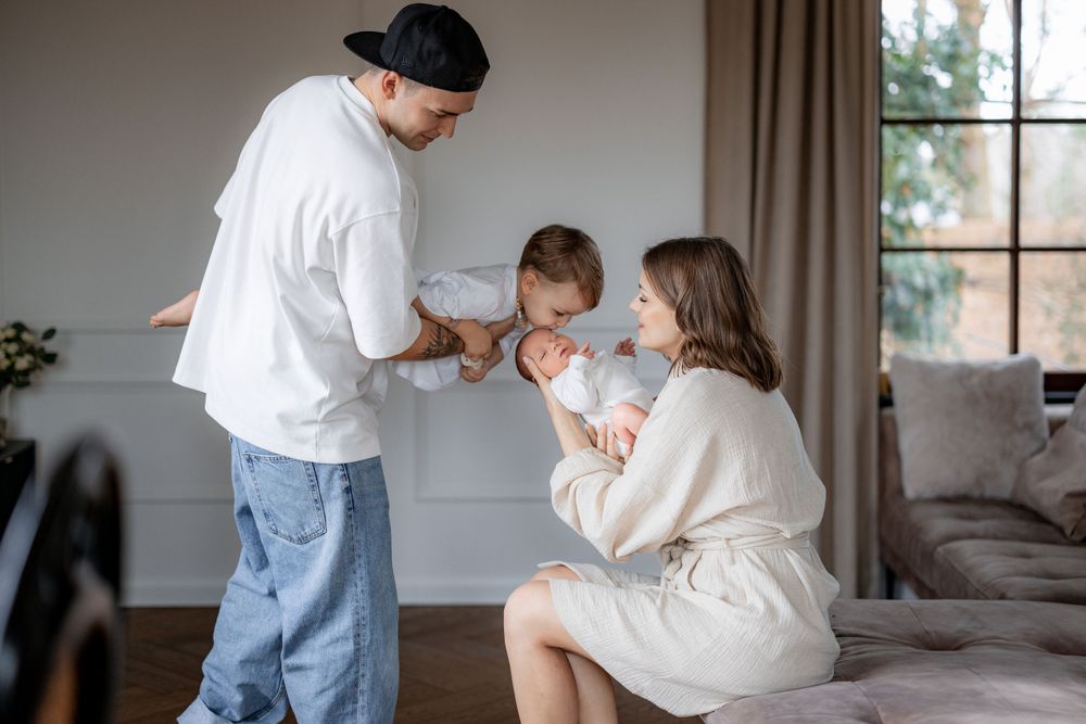 Family sharing intimate moment with newborn baby in cozy home setting.