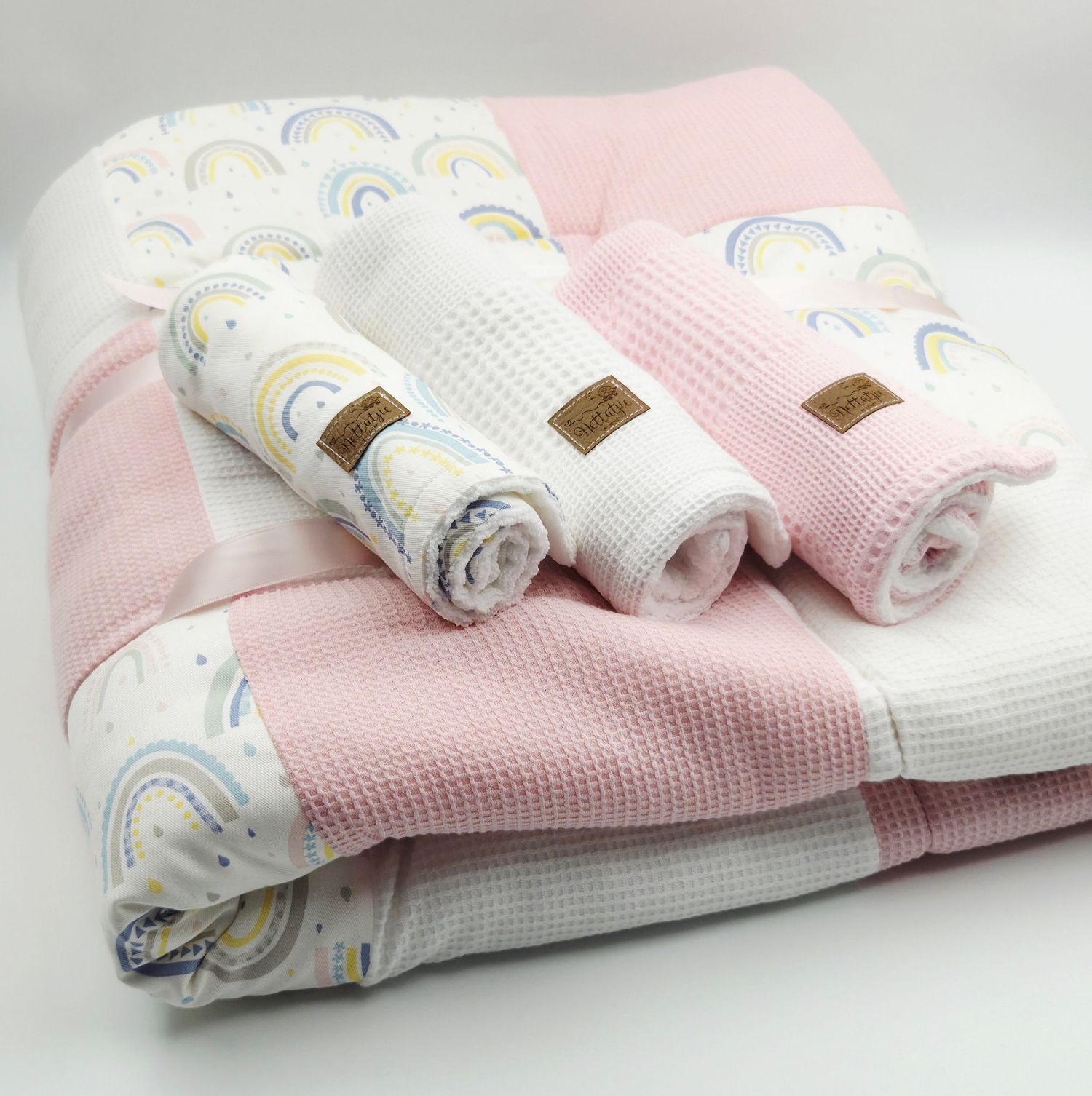 Soft baby blankets with rainbow patterns in pink, white, and pastel colors.