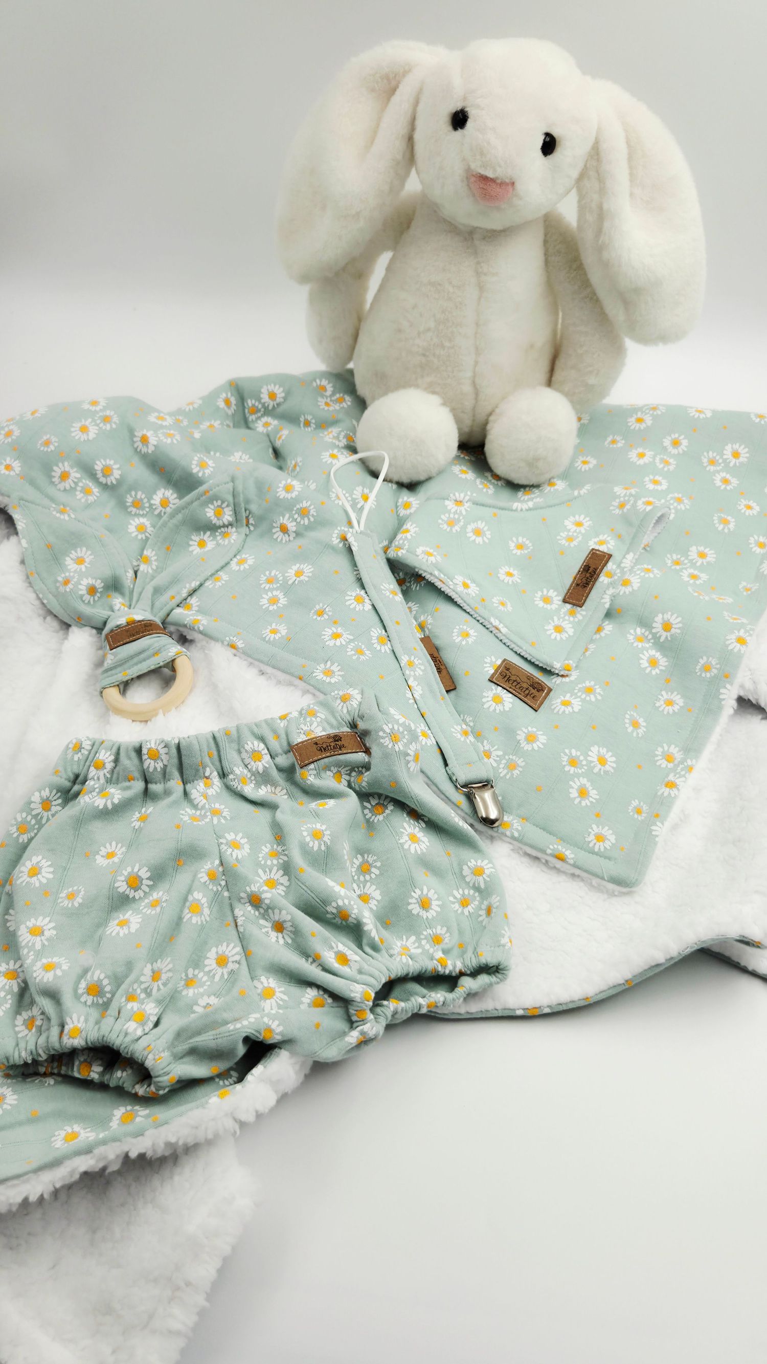 White plush bunny toy with mint floral baby clothes and blanket set in a delicate pattern.