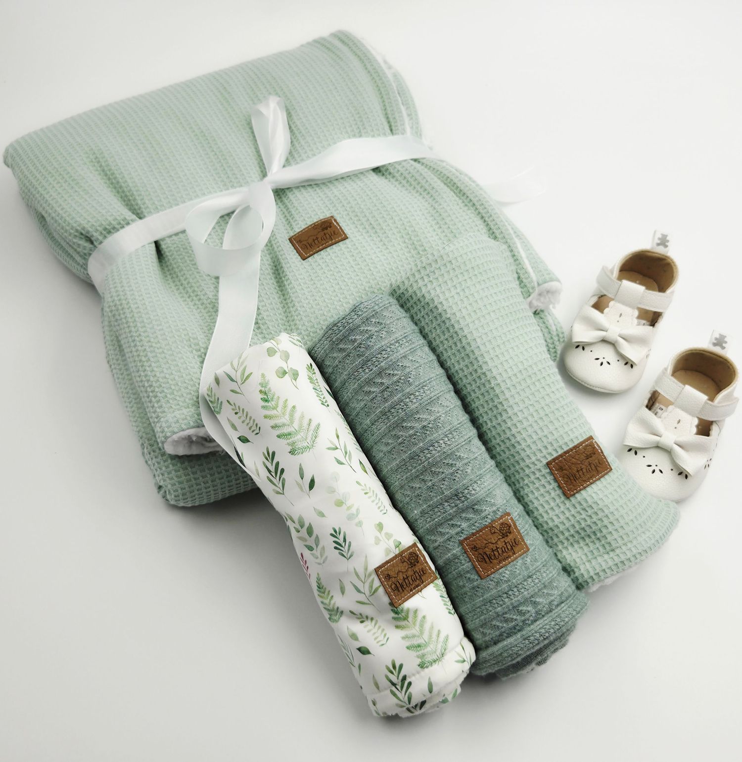 Soft mint green baby blankets and accessories neatly folded and arranged with white ribbons.