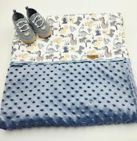 Blue minky dot baby blanket with dinosaur print fabric and small gray baby sneakers on white background.