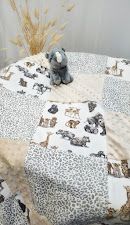 Handmade baby quilt with safari animal and leopard print patches in neutral tones, displayed with a gray elephant plush toy.