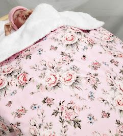 Baby wrapped in pink floral rose print blanket with white sherpa lining.