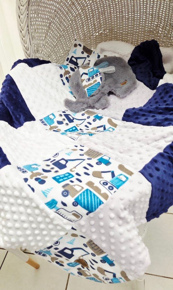 Blue construction vehicle patchwork baby quilt with gray elephant toy.
