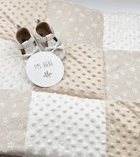 Neutral beige patchwork baby blanket with minky dots, tiny shoes, and a milestone disc on white background.