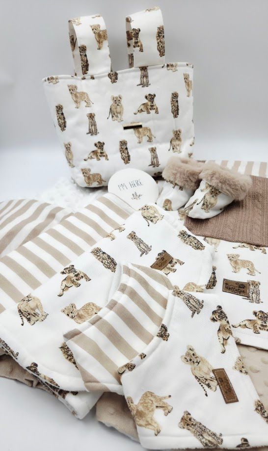 Baby gift set with dog print fabric, striped blanket, booties, and neutral accessories.