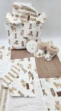 Neutral beige baby gift set with teddy bear print fabric, booties, blanket squares, and gift bag arrangement.