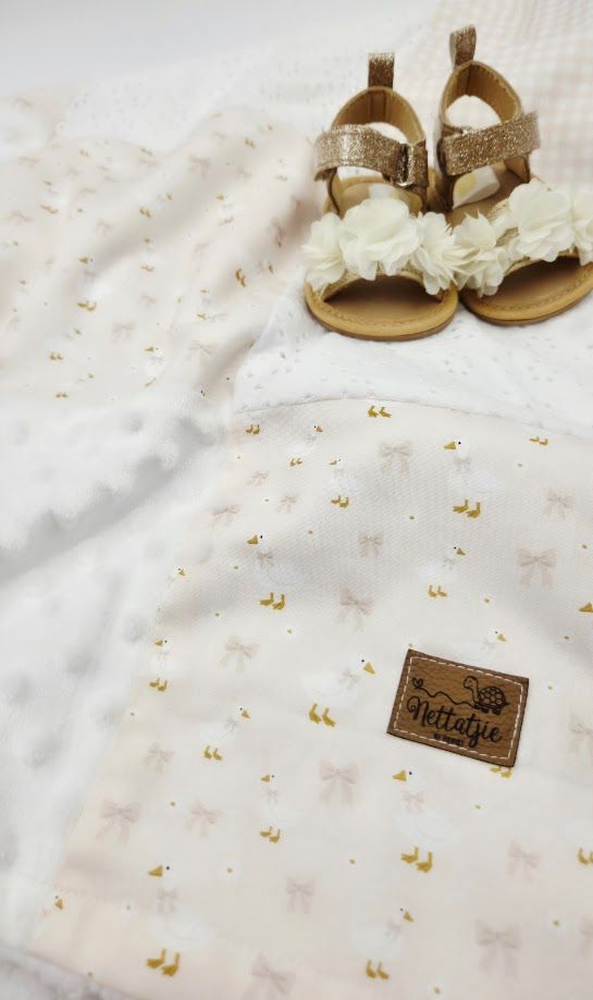 White baby blanket with pink bows and gold dots, paired with sparkly gold sandals and floral headband by Nettafie.