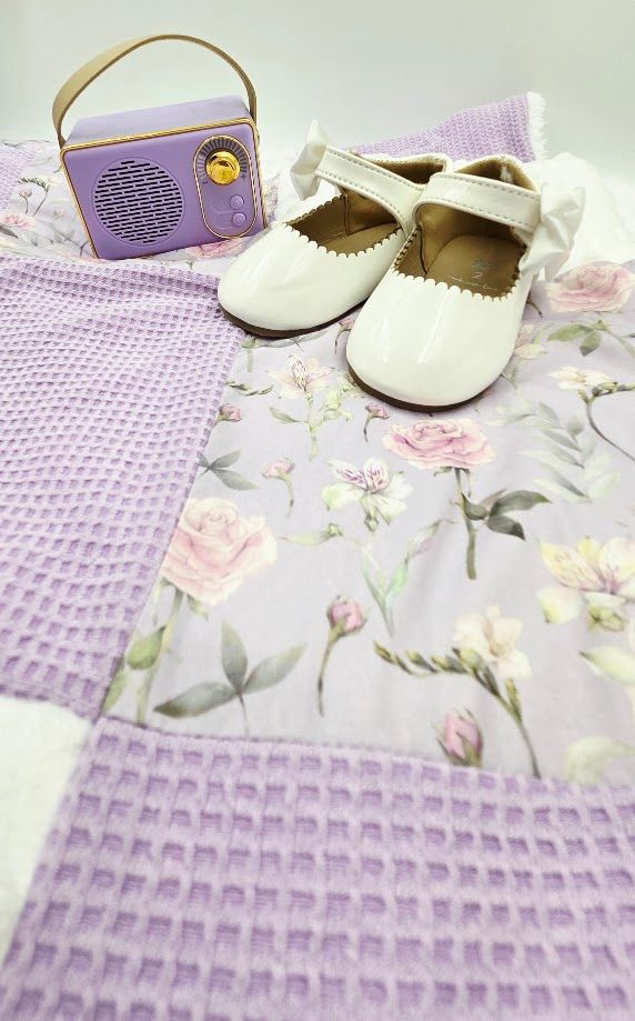 Lavender baby gift set with floral quilt, white patent Mary Jane shoes, and purple retro mini radio speaker.