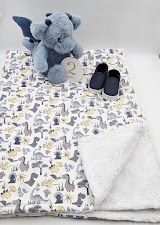 Baby blanket with dinosaur print, blue stuffed dragon, tiny shoes, and sherpa backing displayed together.