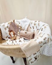 Neutral teddy bear print baby blanket with minky fabric displayed in a wicker Moses basket with plush toy.