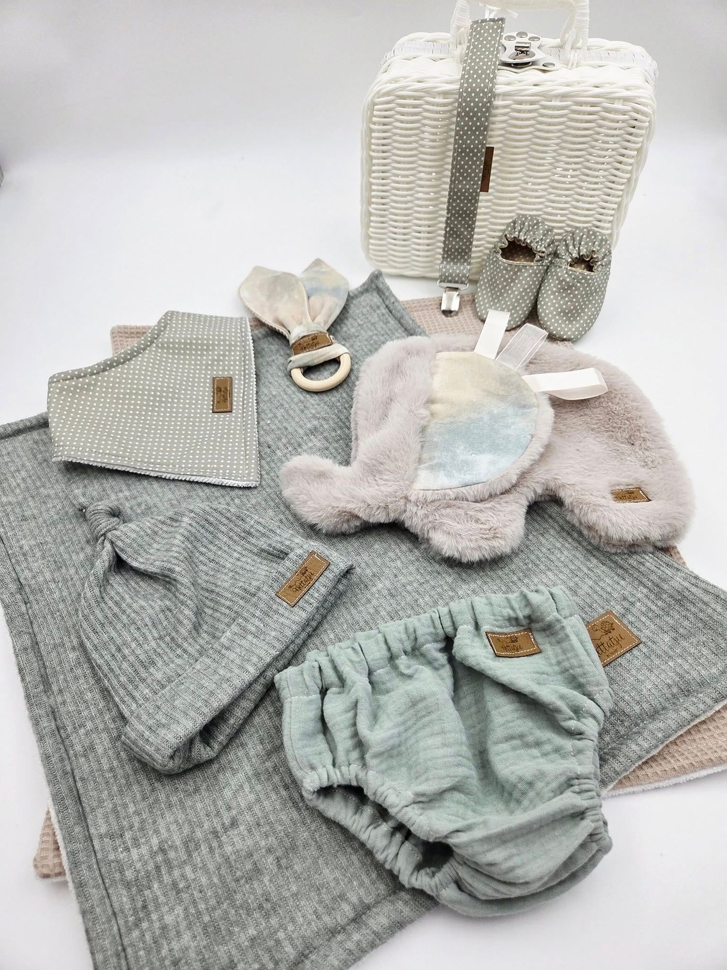 Sage green knitted baby clothing set with matching accessories and blankets.