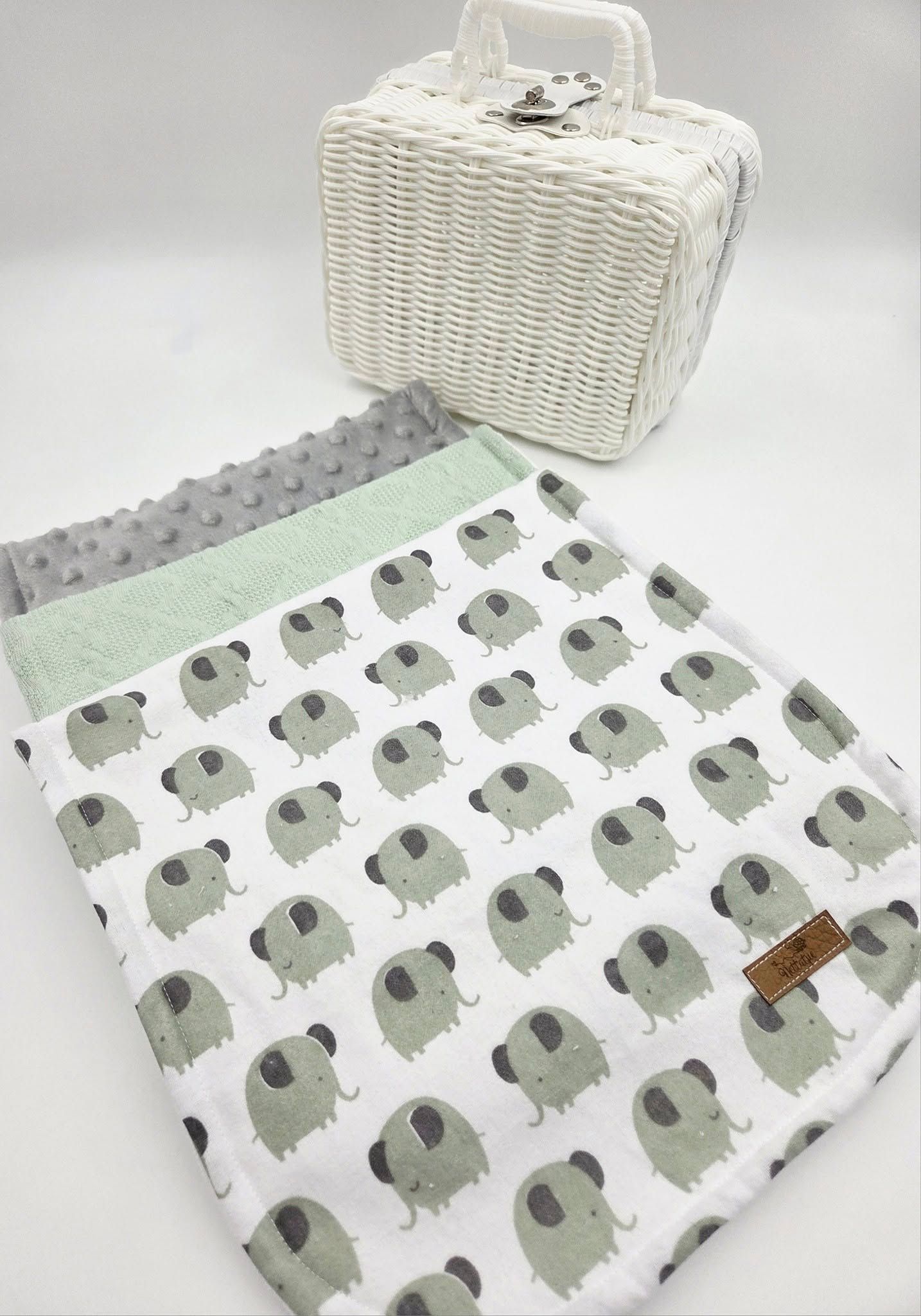 White wicker basket with elephant print baby blanket and mint green accents.