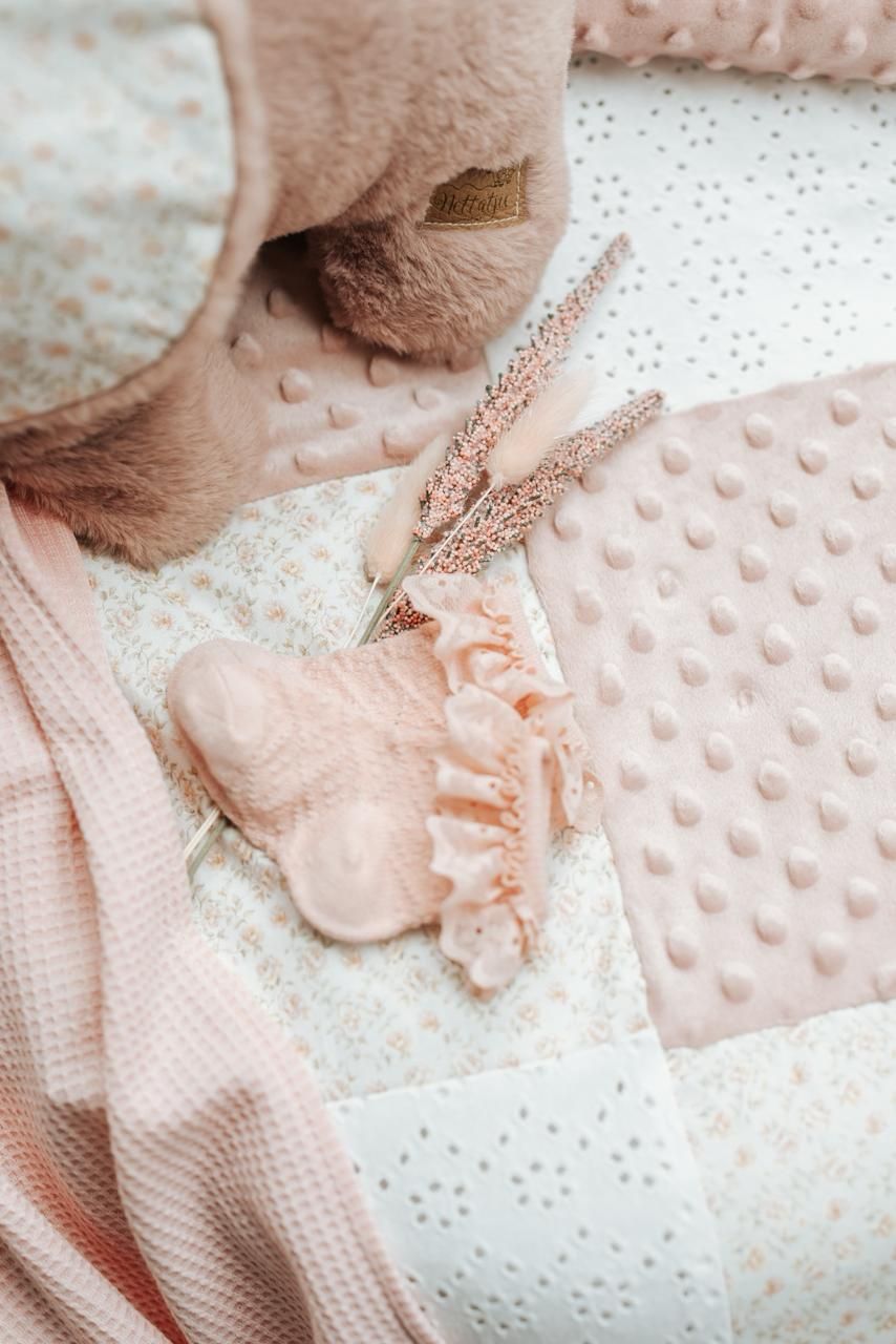 Soft pink and beige textured fabric swatches with delicate ruffles and lace details create a romantic mood board.