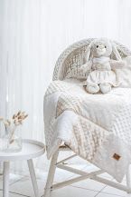 White wicker Moses basket with cream knit blanket and plush bunny toy, styled in a soft neutral nursery setting.