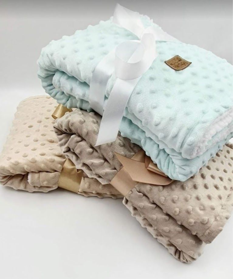 Stack of soft minky dot baby blankets in mint and beige, tied with satin ribbons and a white bow gift wrap.