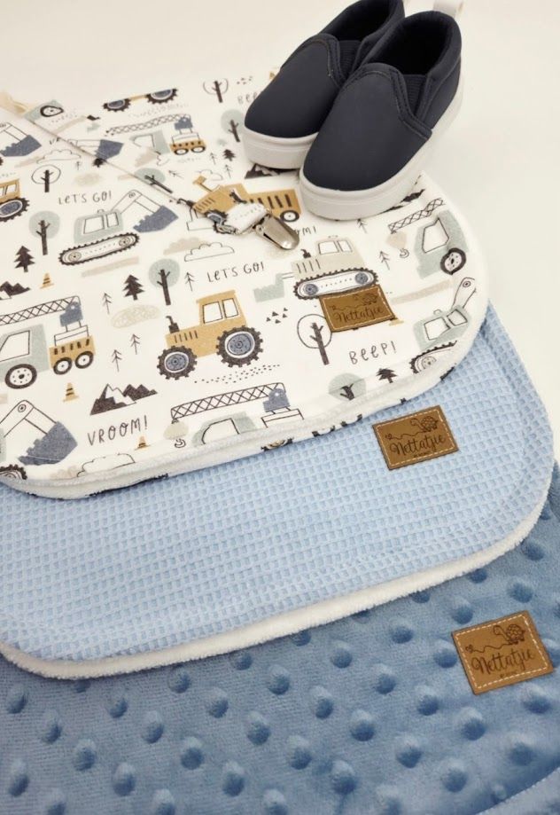 Baby blue minky blanket with construction vehicle print fabric and navy slip-on shoes displayed on white background.