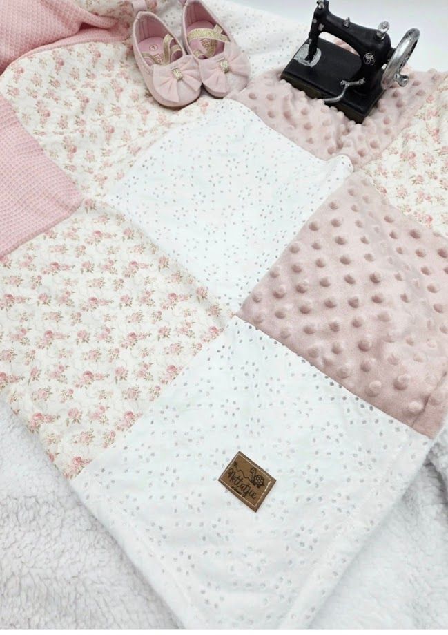 Pink patchwork baby quilt with floral and minky dot fabric squares, displayed with pink shoes and a toy sewing machine.