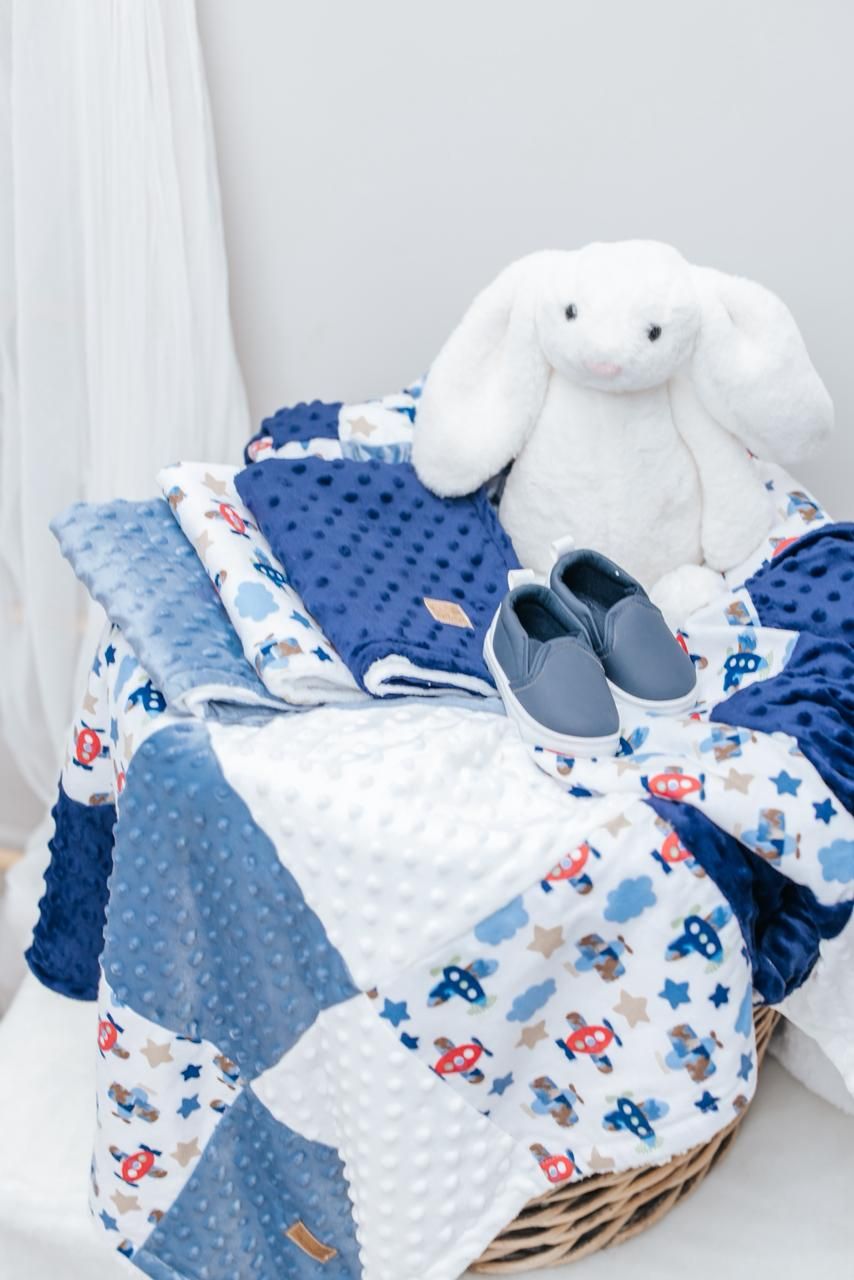 Blue minky blanket with nautical print paired with white plush bunny and baby shoes.