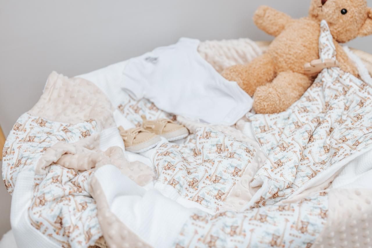Cozy teddy bear nestled in white and beige patterned bedding.