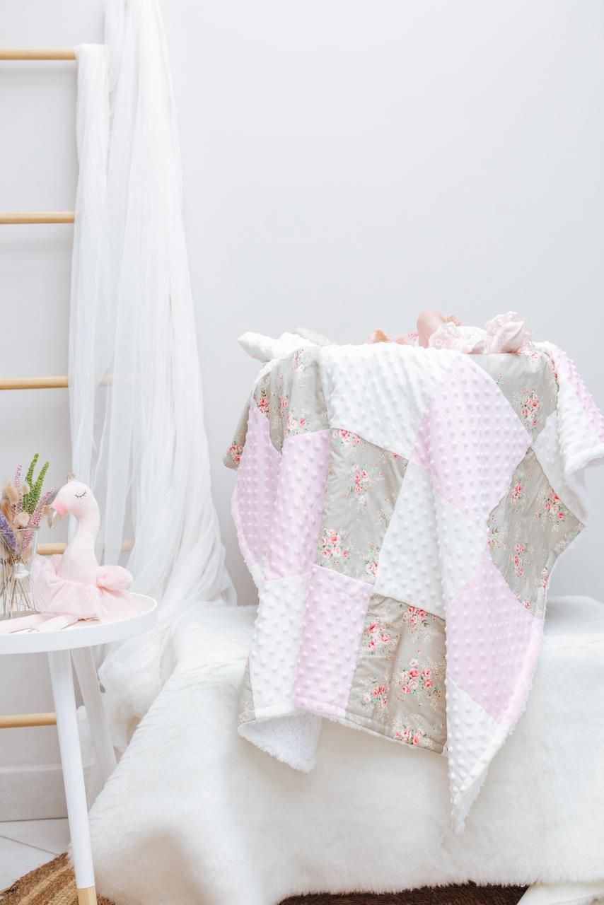 Pink and white minky blankets with floral patterns draped over white furniture.
