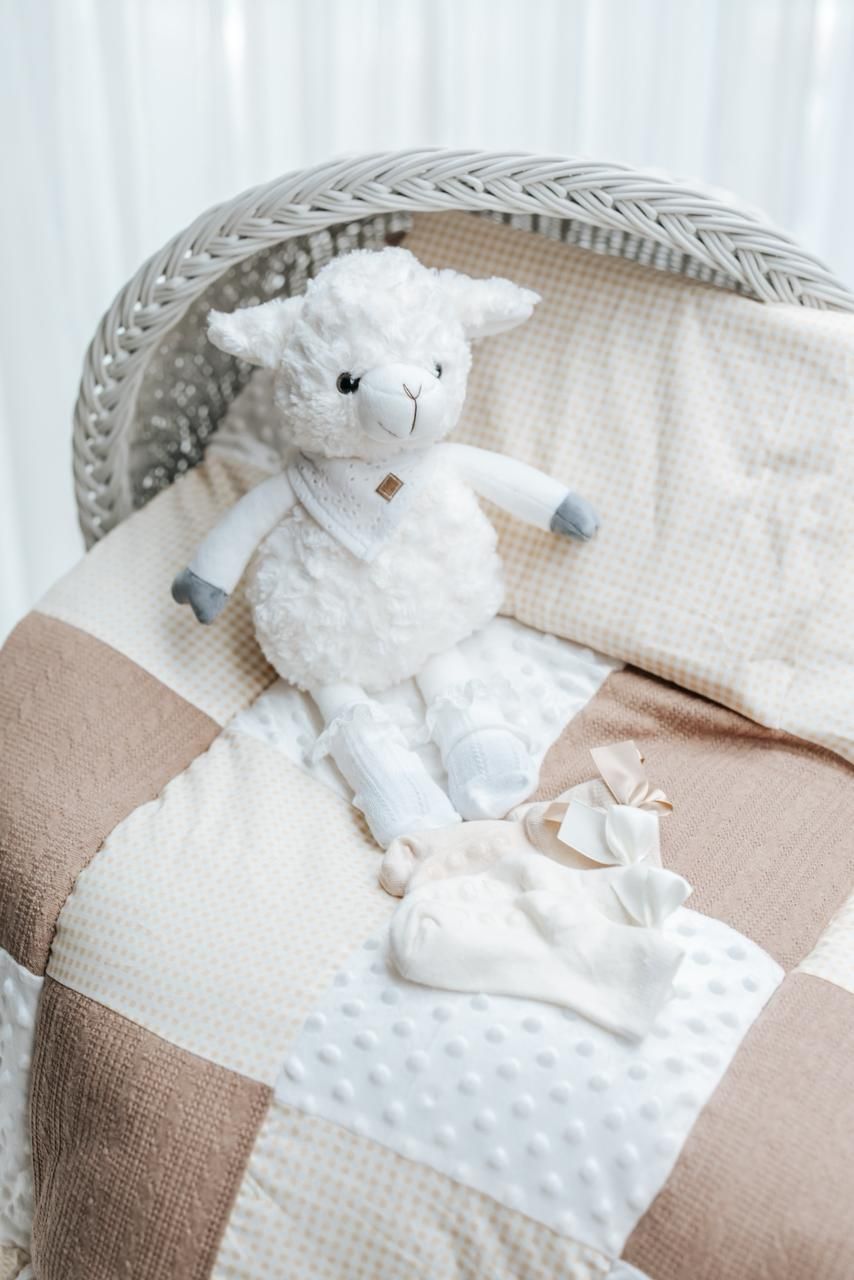 White plush lamb toy resting on a textured beige and white cushion with minky dot fabric.