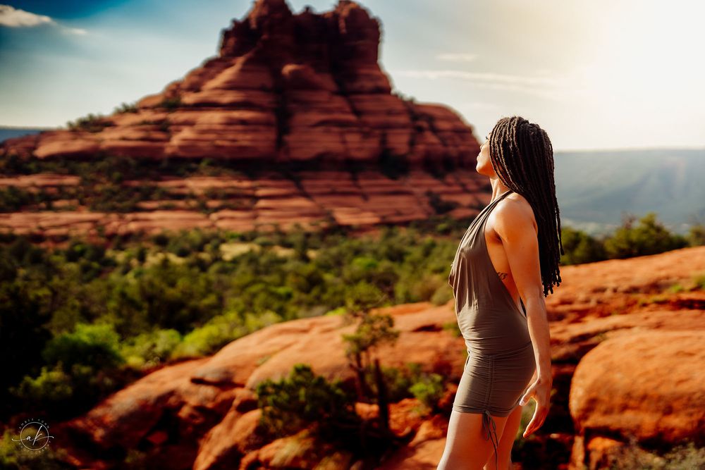 Woman in gray bodysuit gazing at iconic Bell Rock formation in Sedona Arizona at sunset.