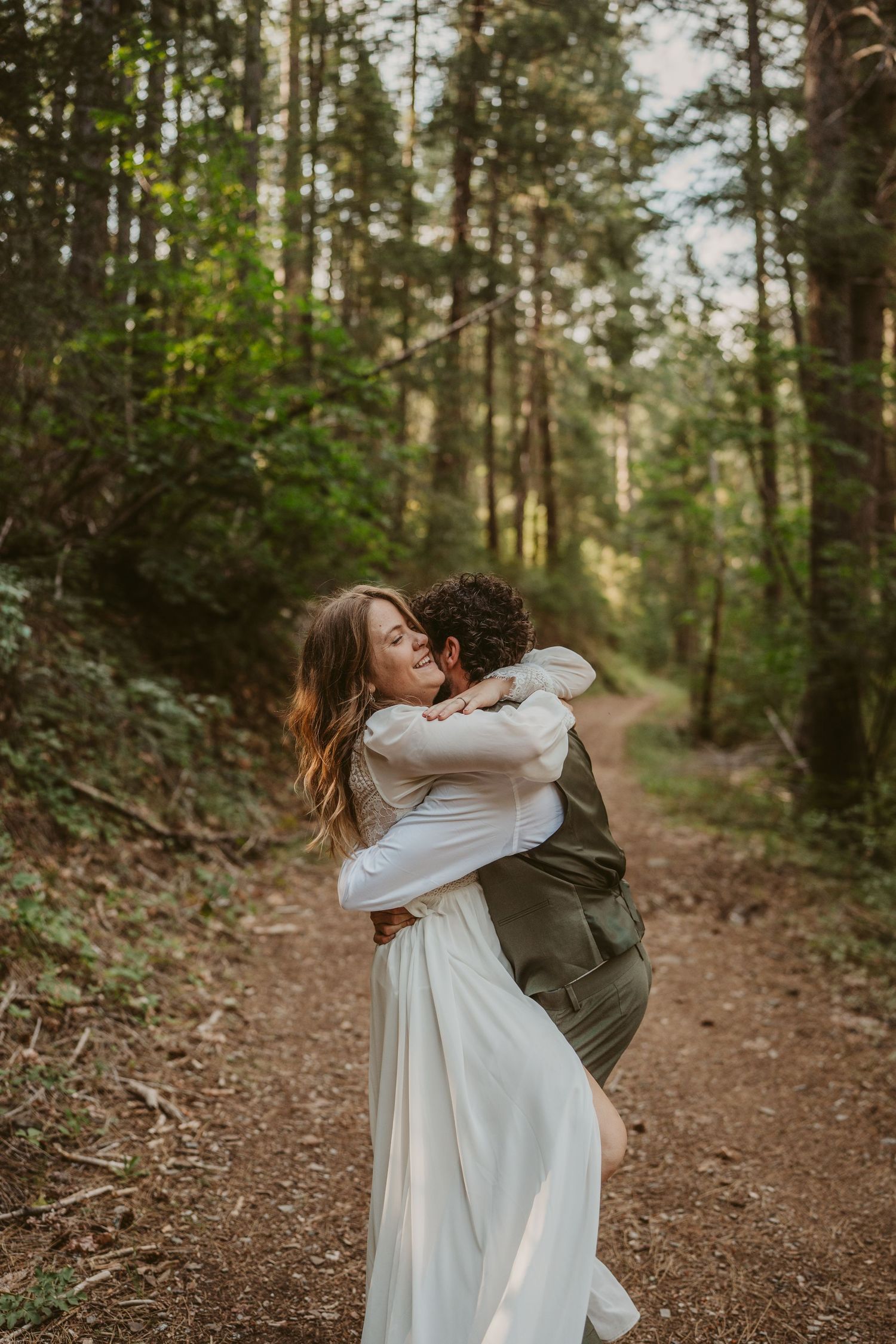 Elegant wedding scene with the bride wearing a flowing backless white dress with ruffles and the groom in a navy suit and orange tie.