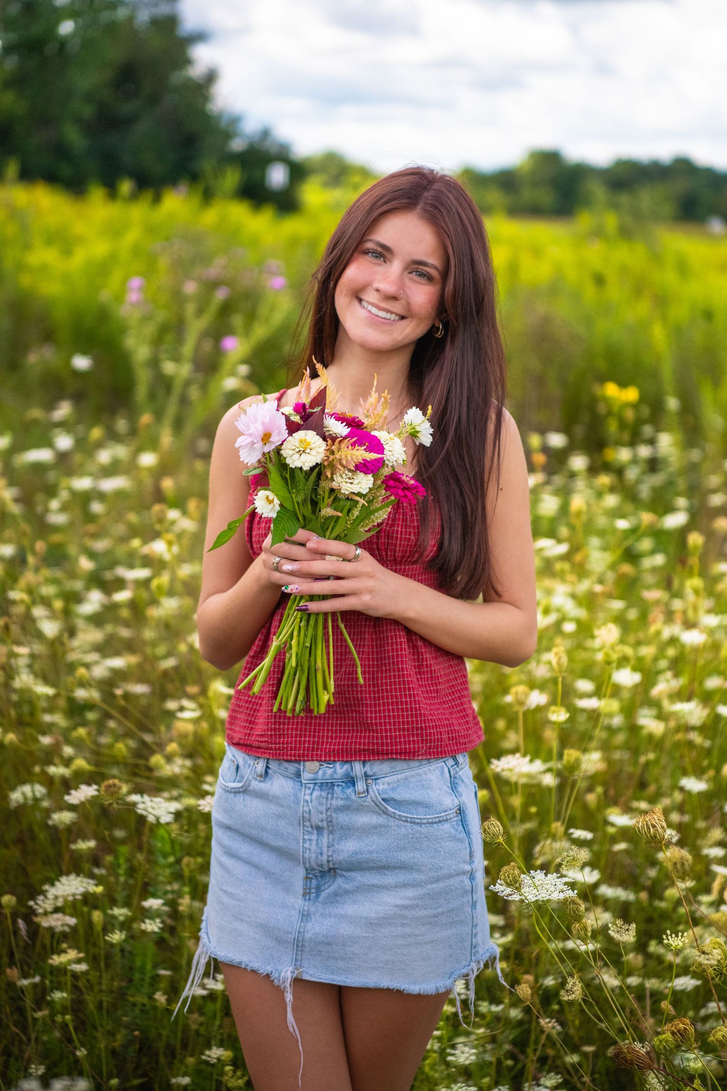 Person enjoying a summer day in a wildflower field holding a colorful bouquet of fresh flowers.