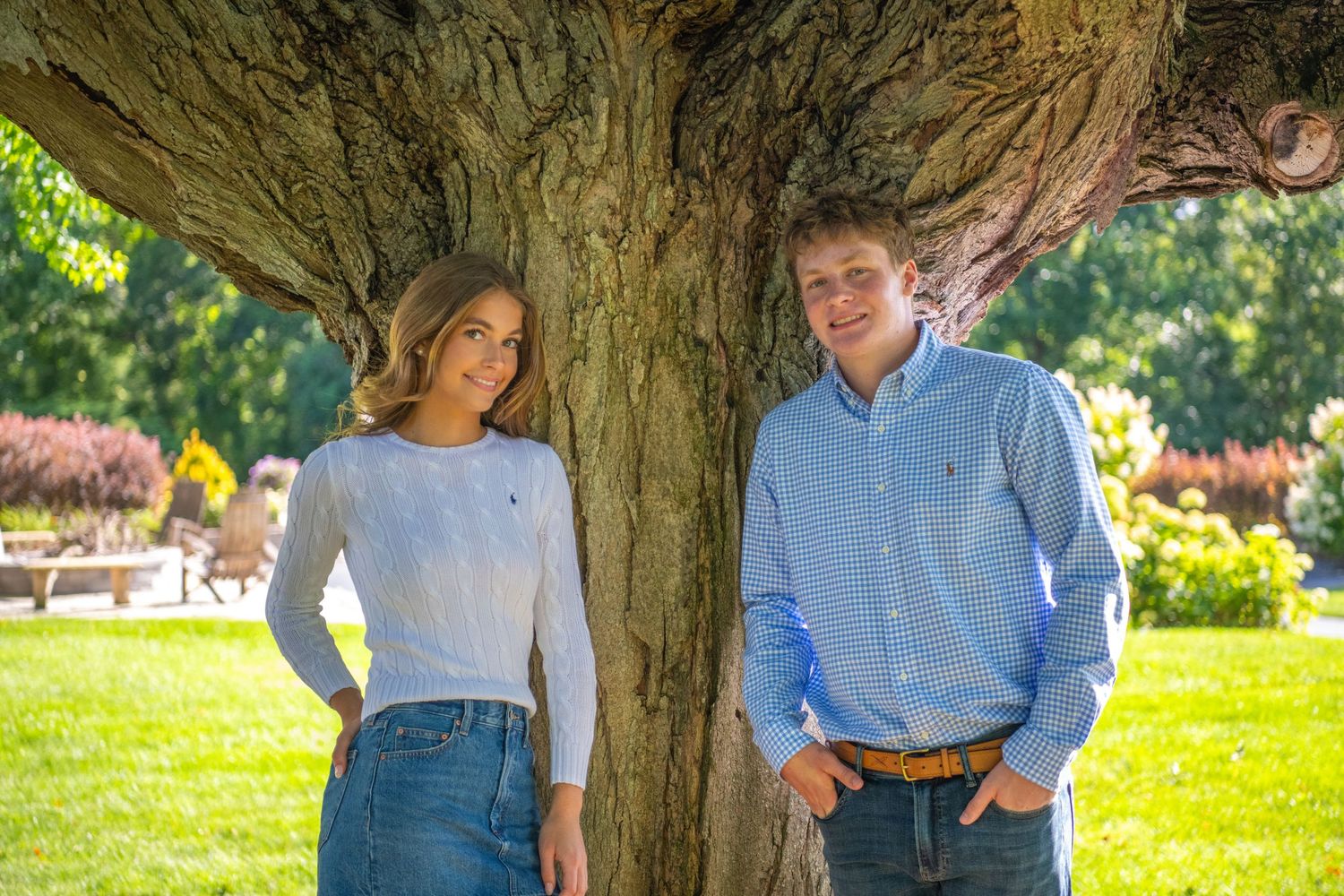 Two people in coordinating light blue outfits walking together in a sunny park setting.