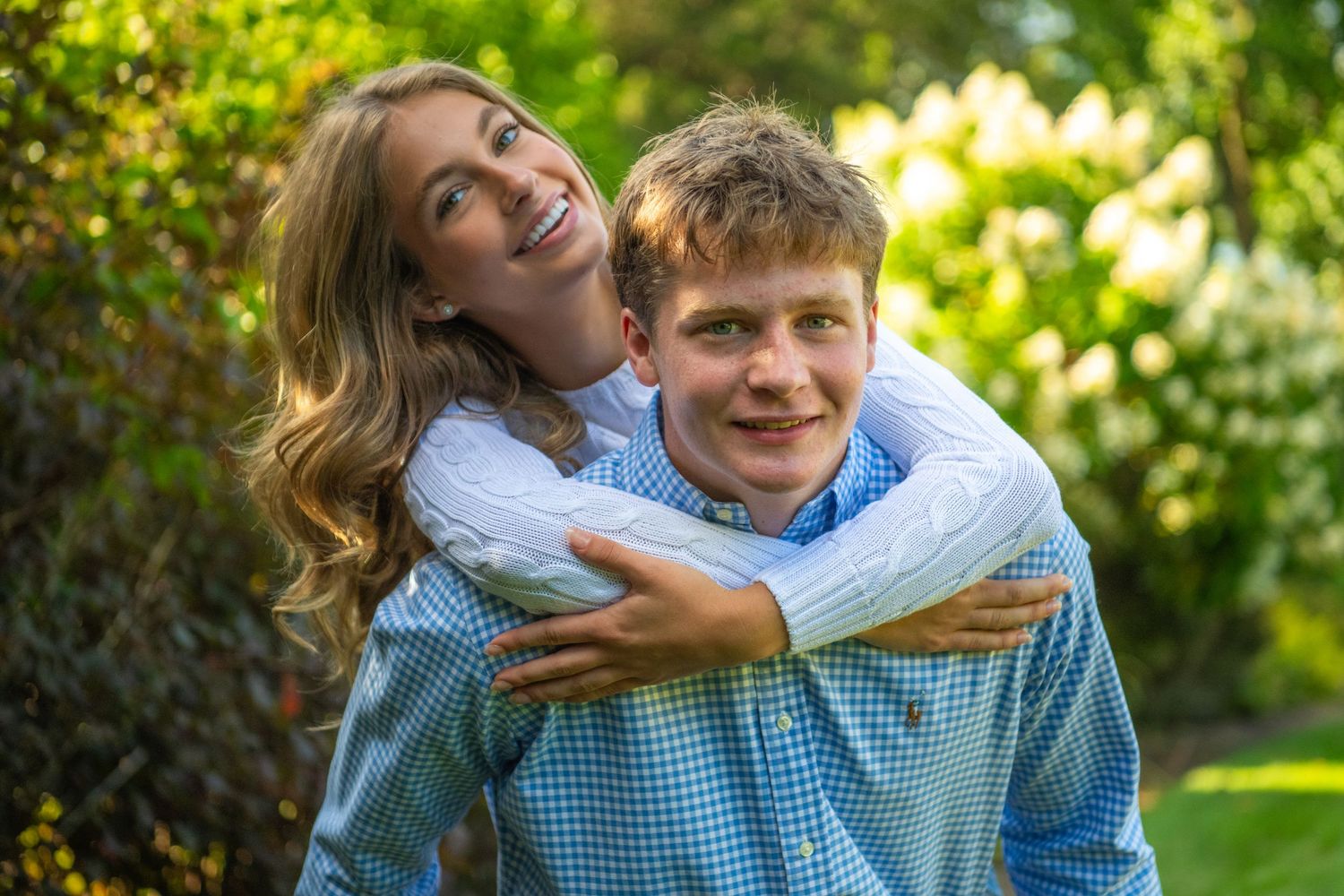 Two people share joyful moments outdoors in a bright sunlit garden setting wearing coordinated blue outfits.