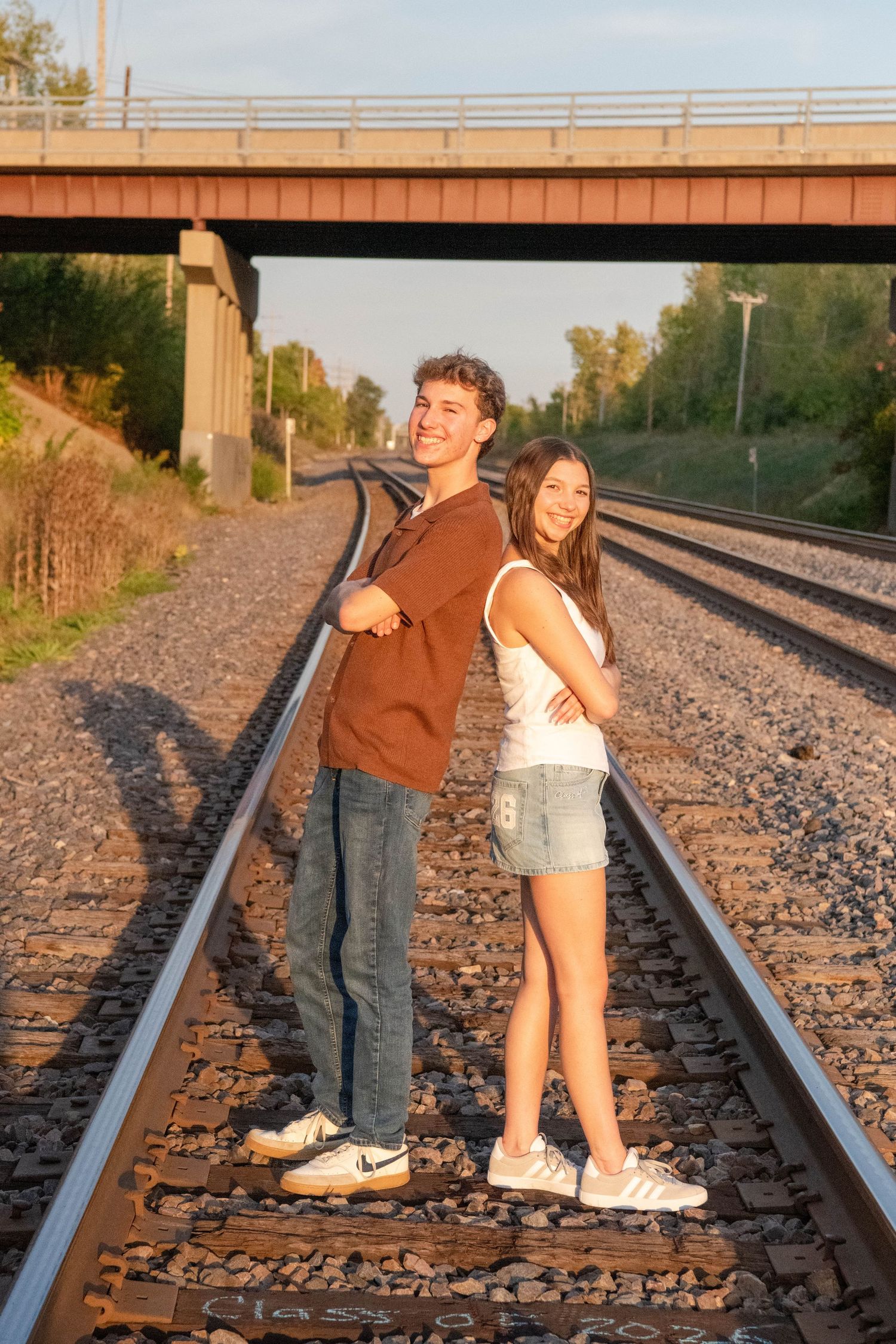 Two people pose playfully on train tracks at sunset creating a series of romantic silhouettes.