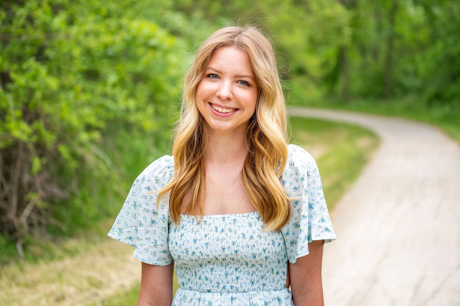 Portrait session on nature path with bright green foliage in background.