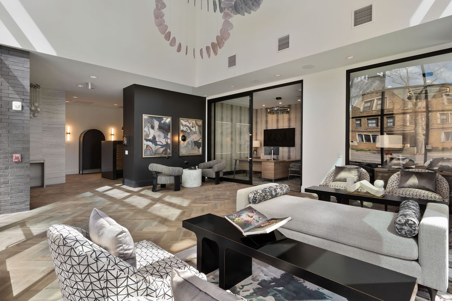 Contemporary luxury apartment leasing office with black and white decor, glass walls, and modern furnishings in neutral tones.