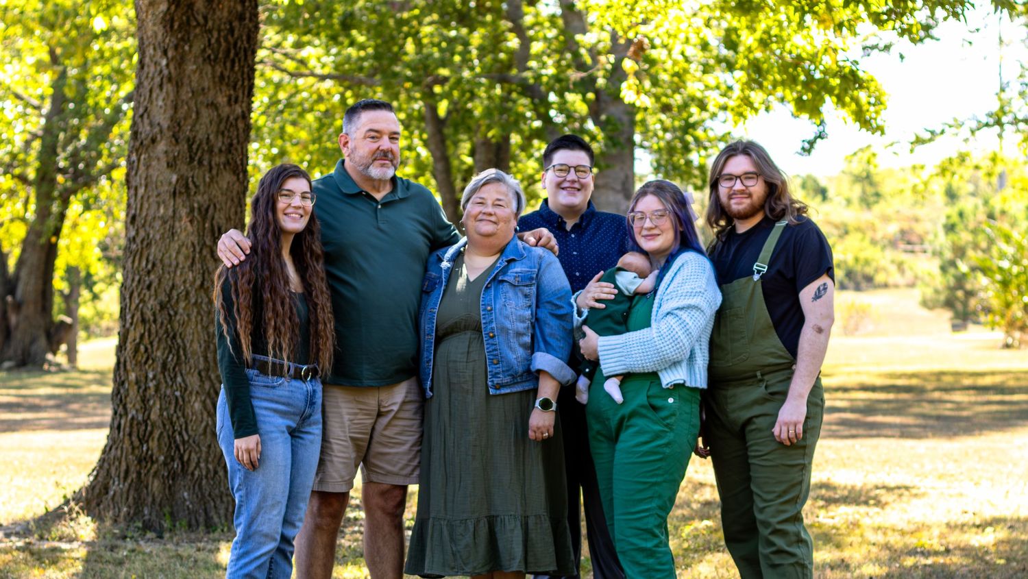 Happy family enjoying quality time together outdoors on a sunny autumn day with colorful fall foliage in the background.