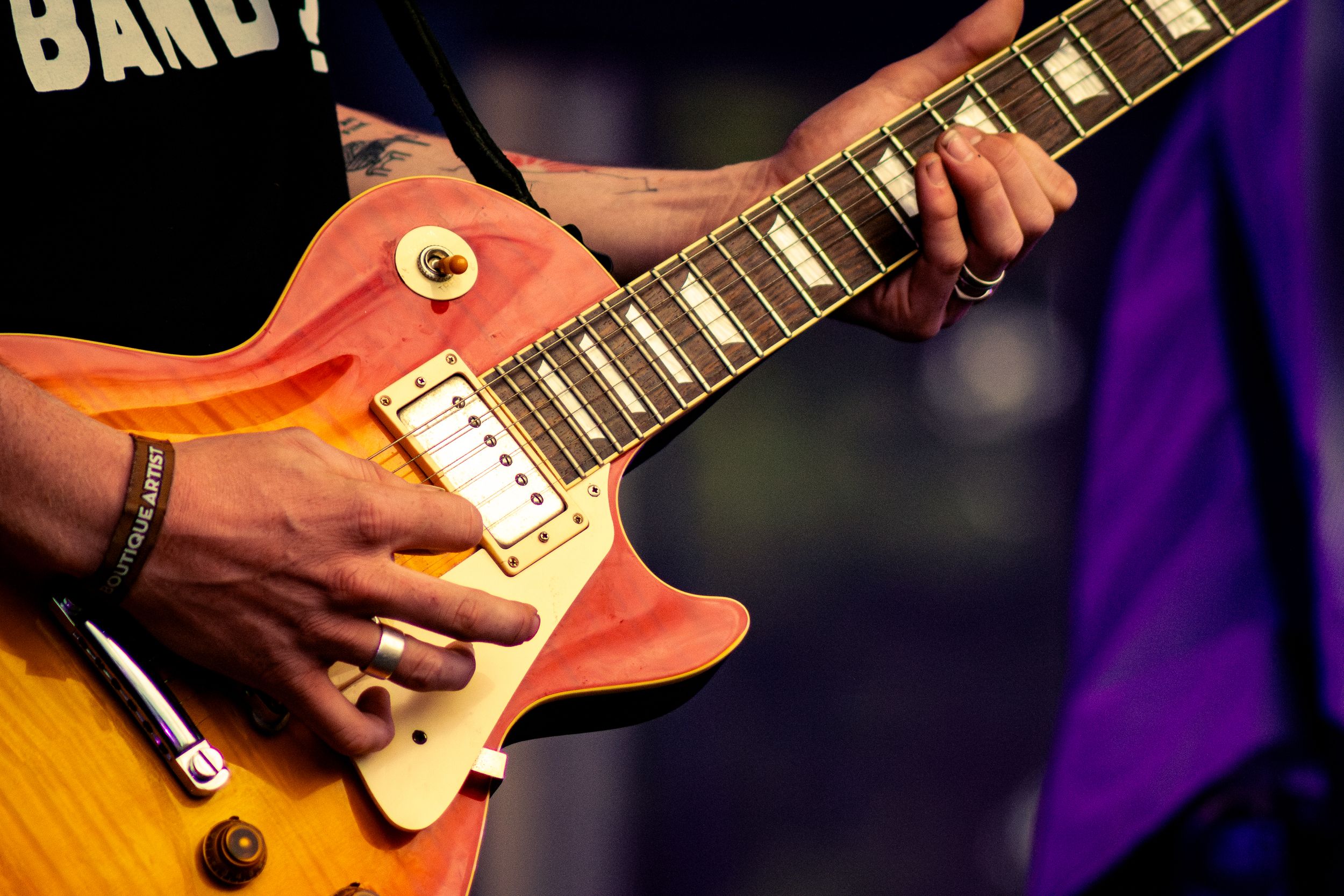 Close-up shot of hands playing sunburst Les Paul electric guitar on stage.