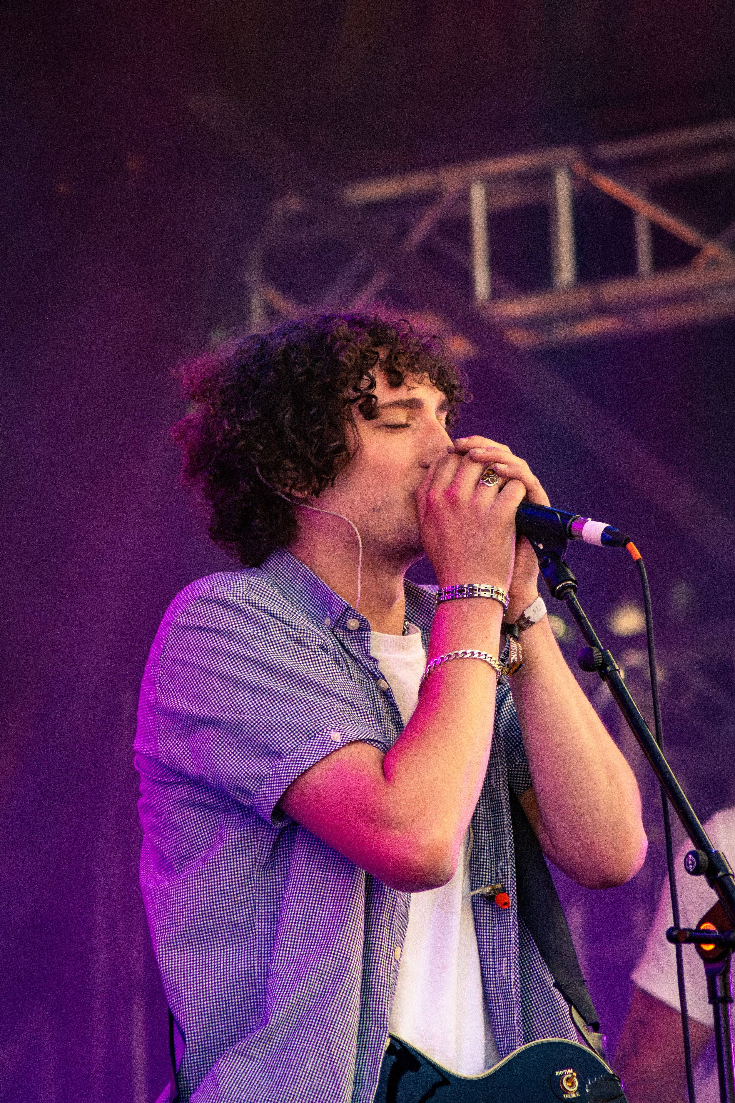 Close-up of singer performing emotionally into microphone under purple stage lighting.