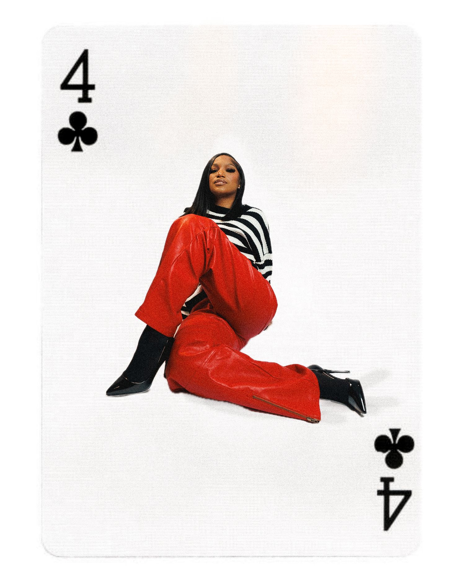 A playing card showing a figure in a bright red jumpsuit and striped top posing against a white background with club suit symbols.