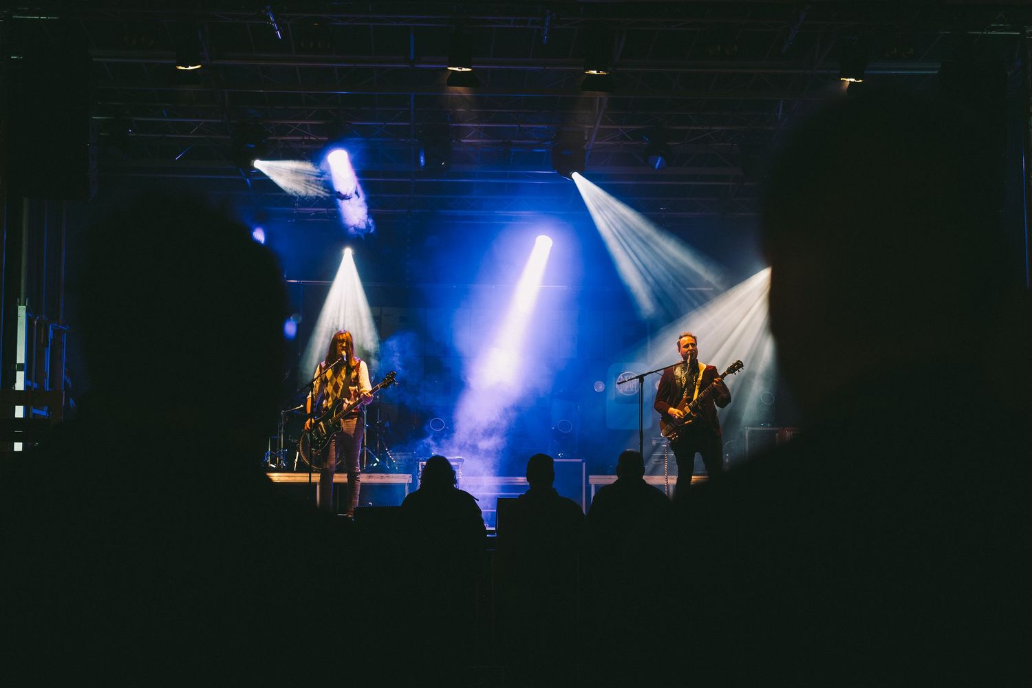 Concert venue with dramatic blue stage lighting and fog effects creating an atmospheric ambiance.