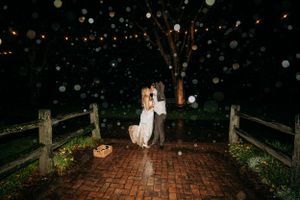 A couple dances together on a brick patio surrounded by twinkling lights at night.