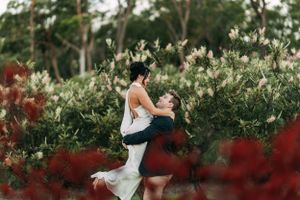 Romantic lift pose among blooming white and red flowers in a garden setting.