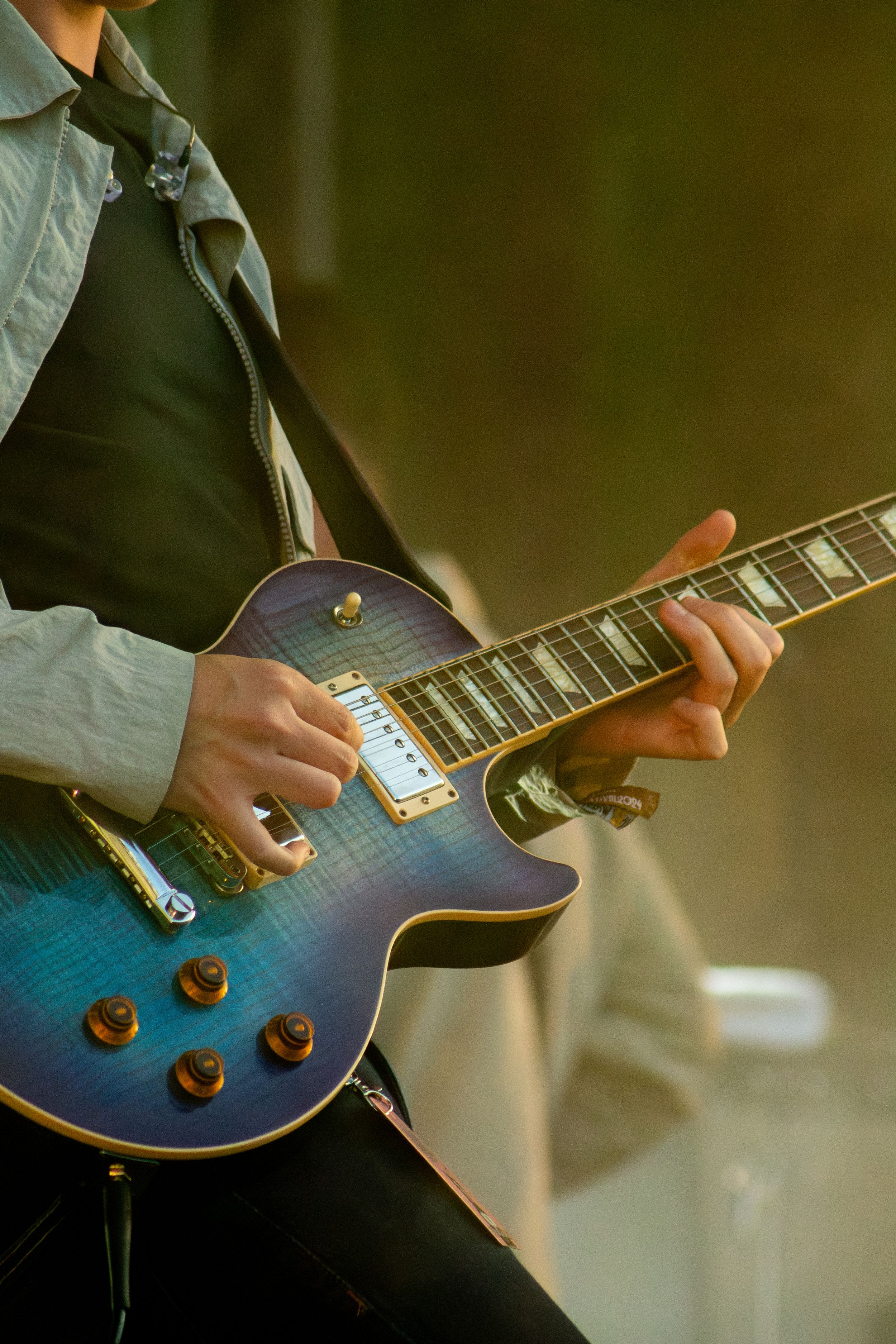 Close-up of hands playing blue Les Paul style electric guitar during live performance.