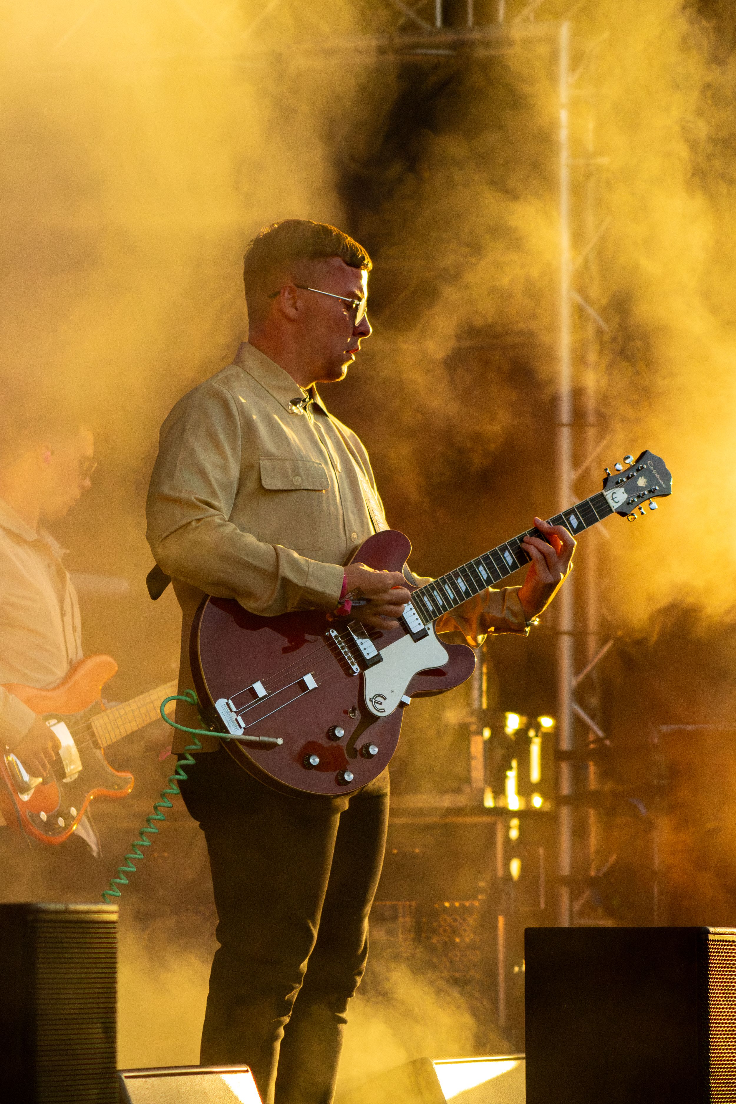 Guitarist performs with vintage-style electric guitar amid golden smoke on concert stage.