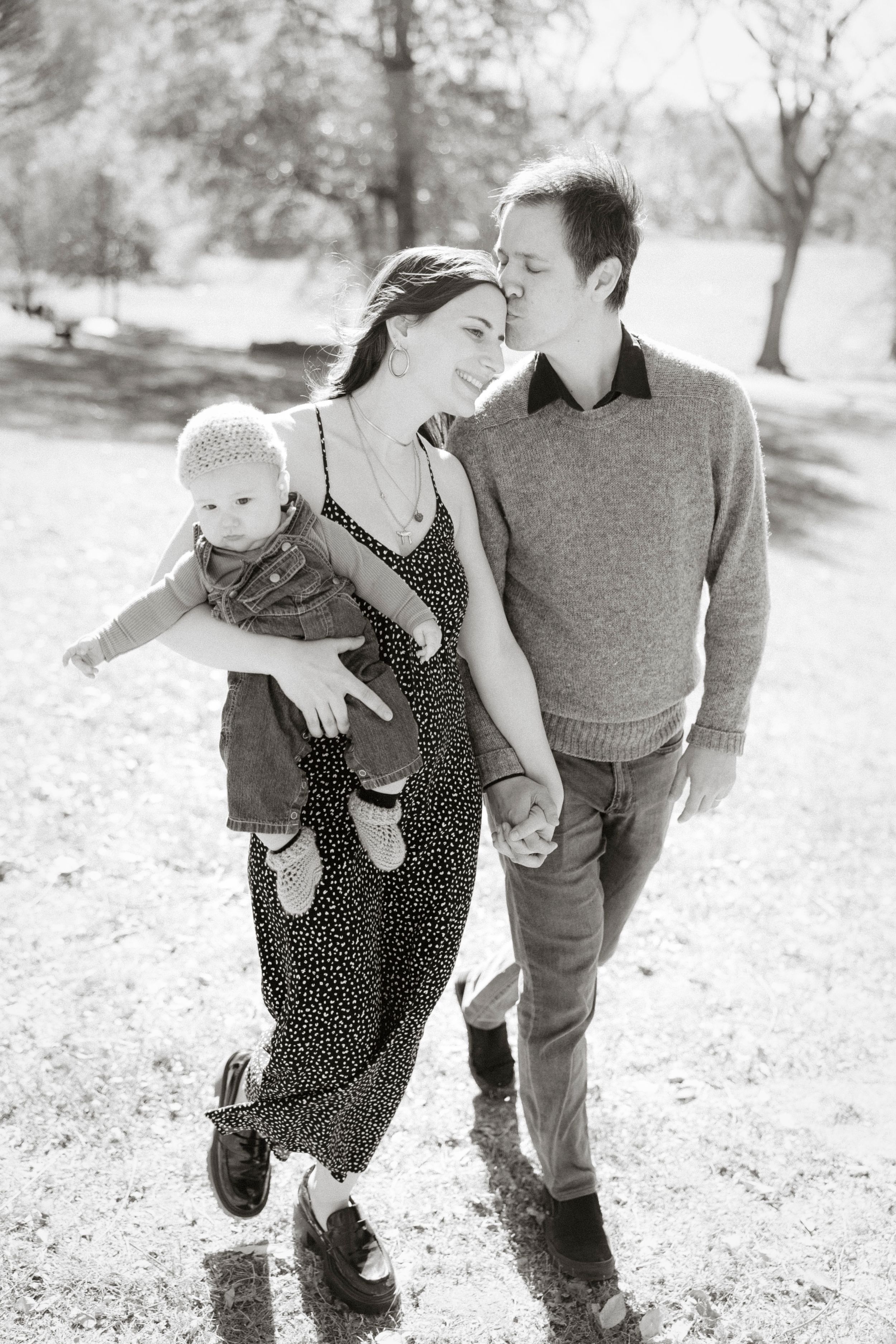 A family takes a casual stroll together in a park on a sunny afternoon.