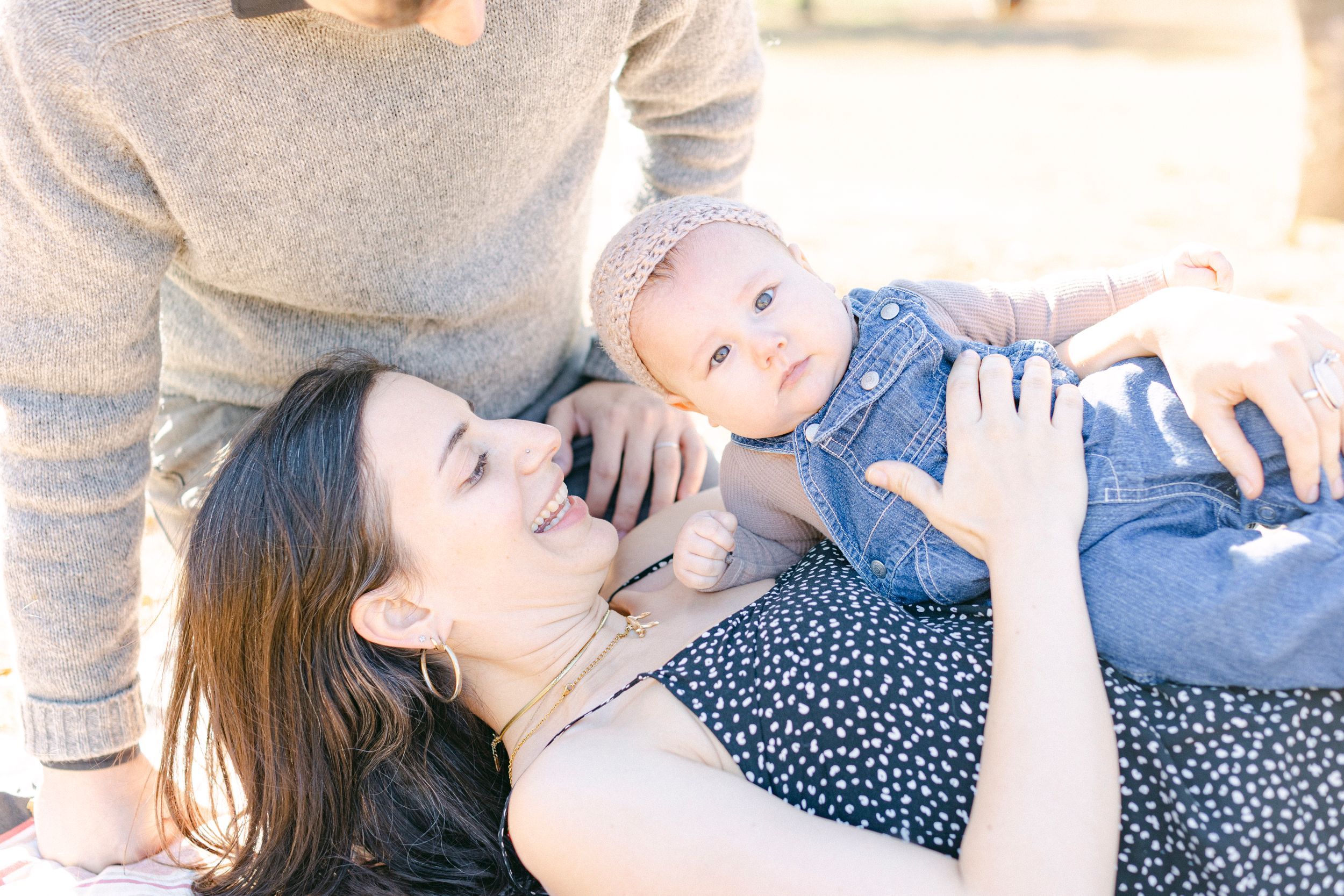 Sweet candid moment with baby in denim against natural outdoor backdrop.