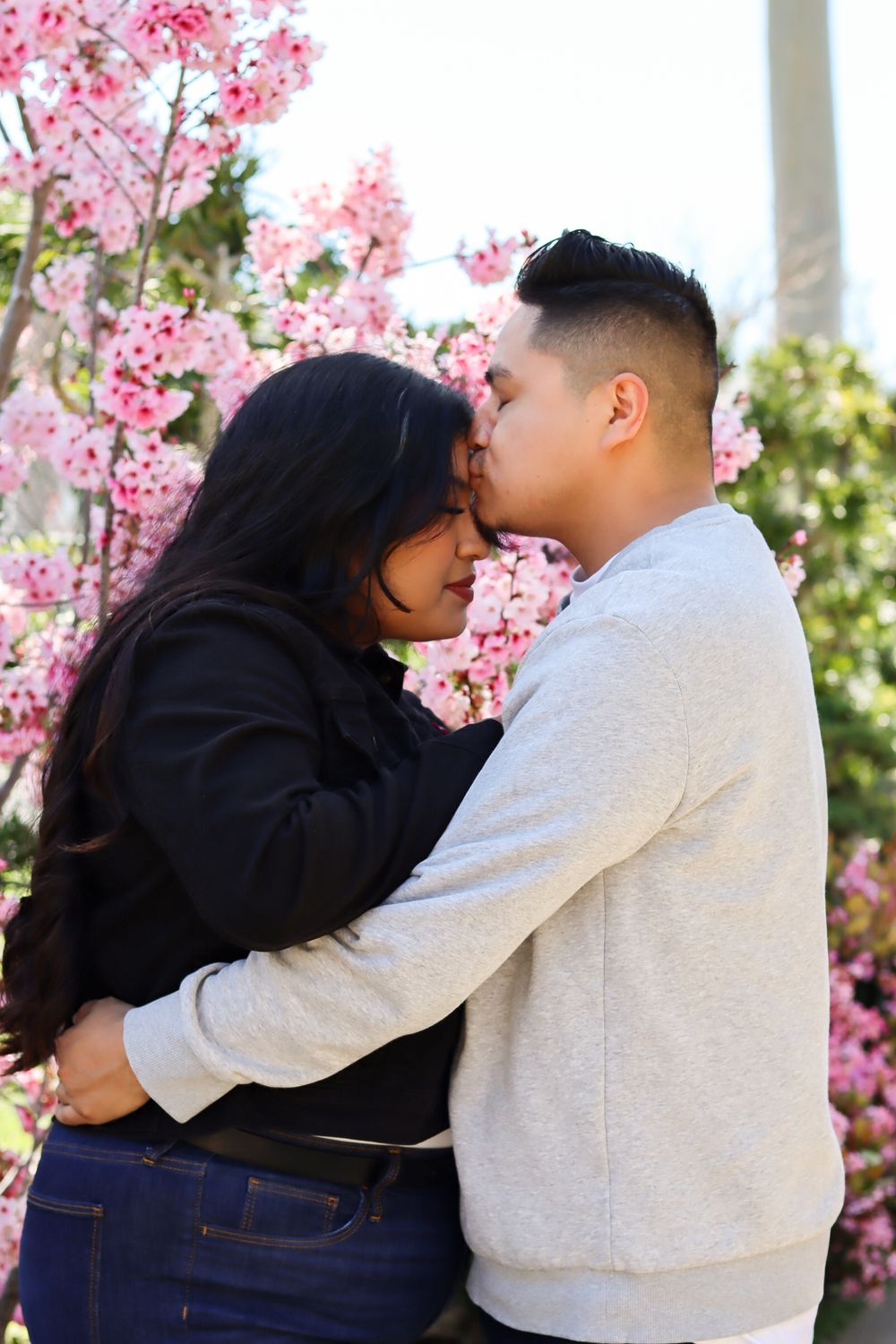 Couple embracing near blooming cherry blossoms in springtime.